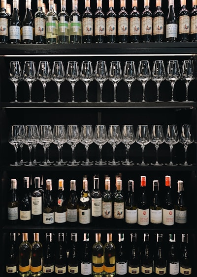 Shelves display rows of wine bottles and neatly arranged wine glasses. Various wine labels are visible, showcasing a diverse selection of bottles.