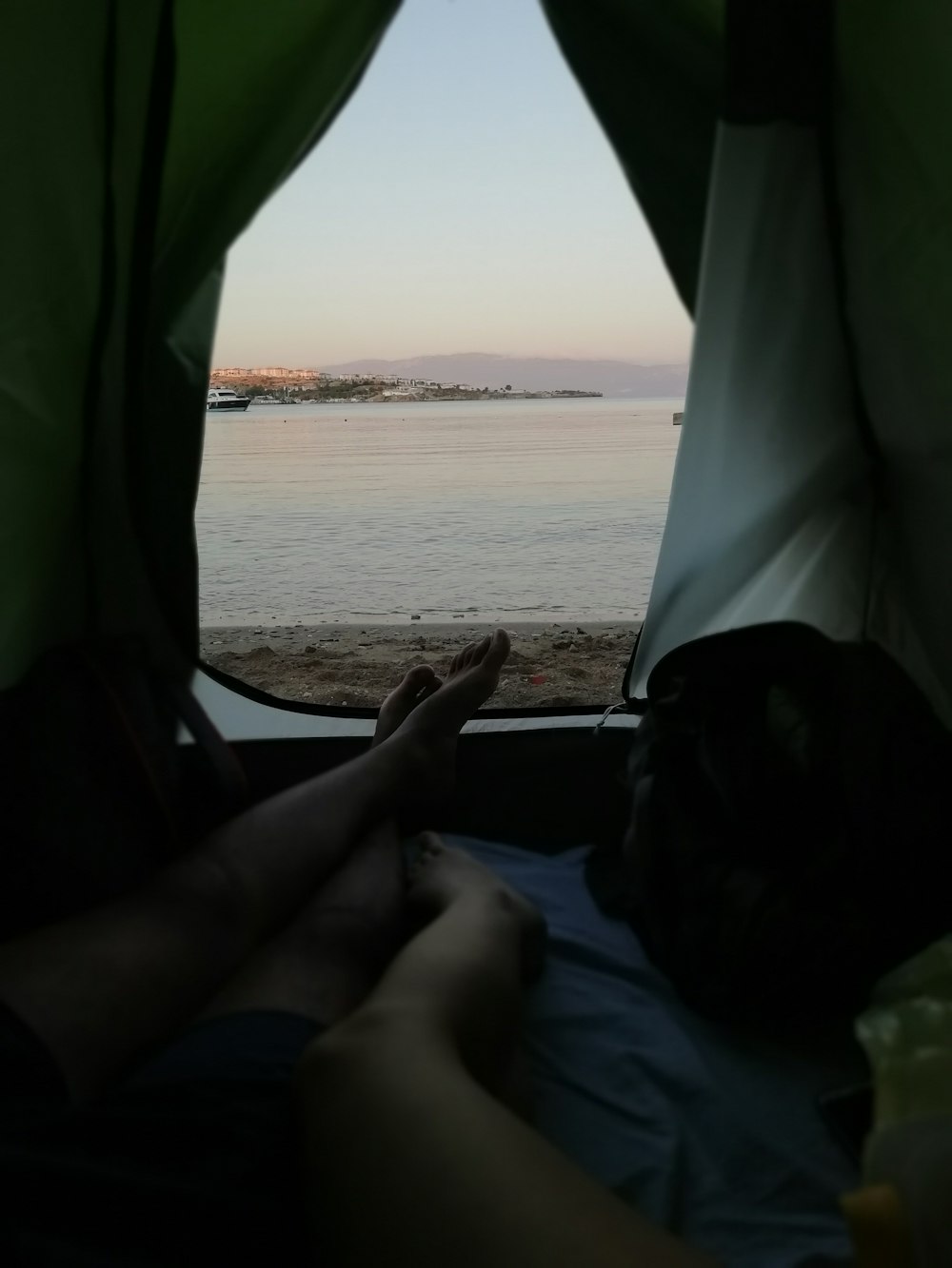 two people lying down inside a tent by the beach