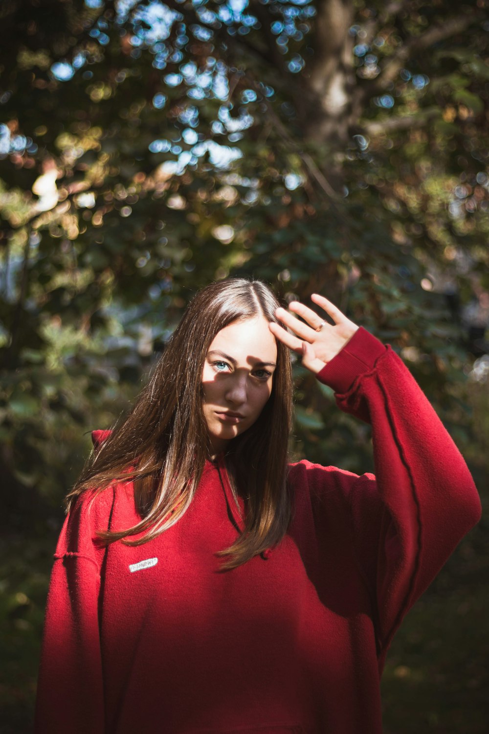 woman wearing red sweater standing beside tree