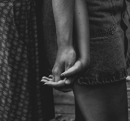 a black and white photo of two people holding hands