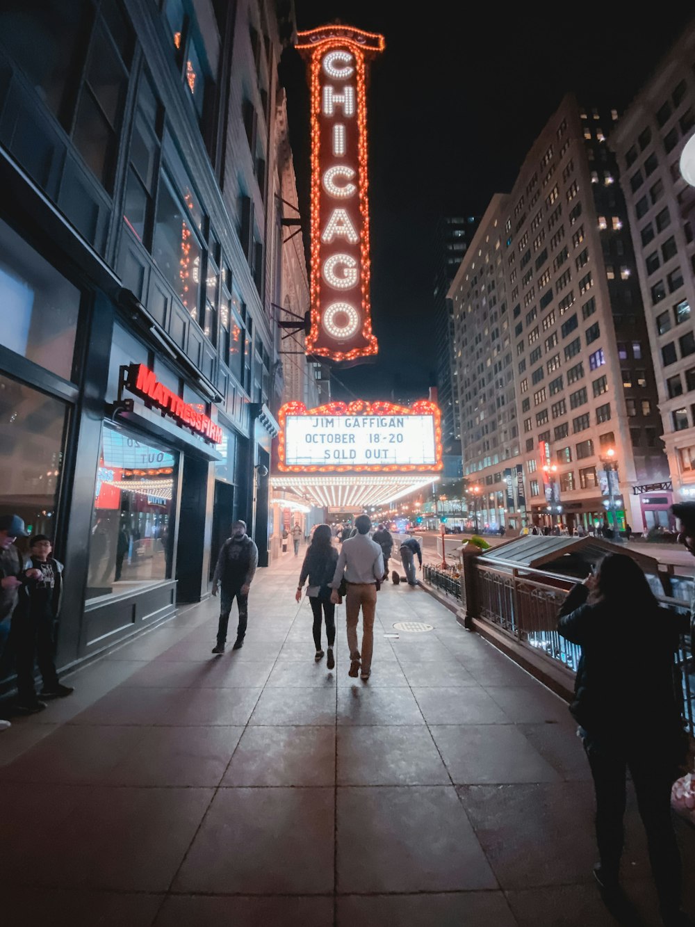 people walking in front of establishment with Chicago lighted sign
