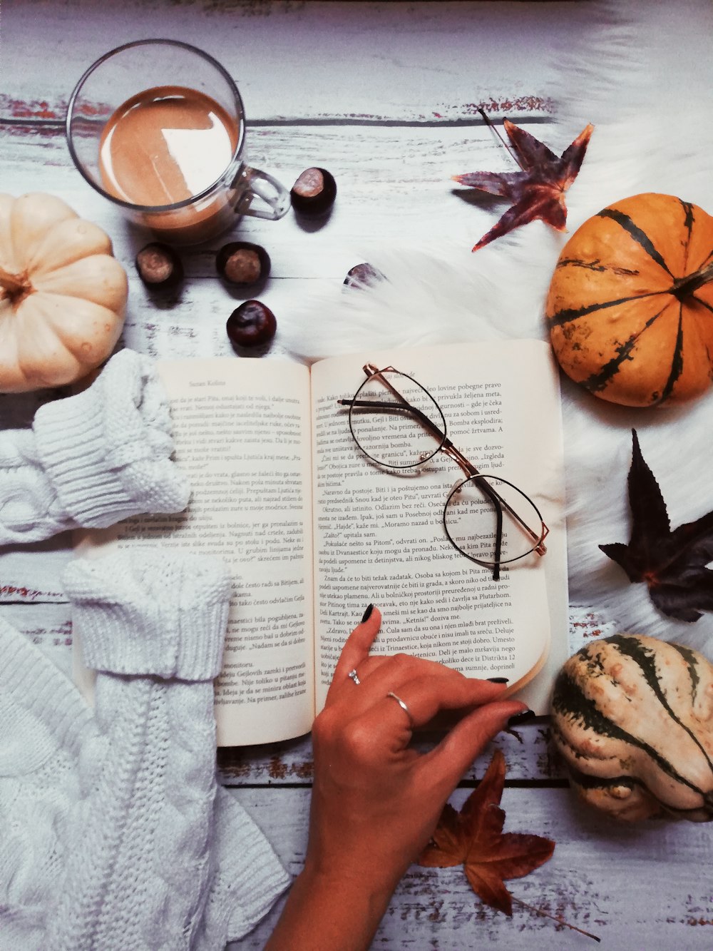woman about to turn the page surrounded with gourds and glass of coffee