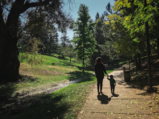 A warm scene of a parent and child holding hands in a sunlit park, symbolizing care and protection.