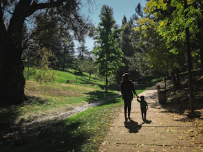 A cozy scene of a child holding hands with both parents, walking through a park.