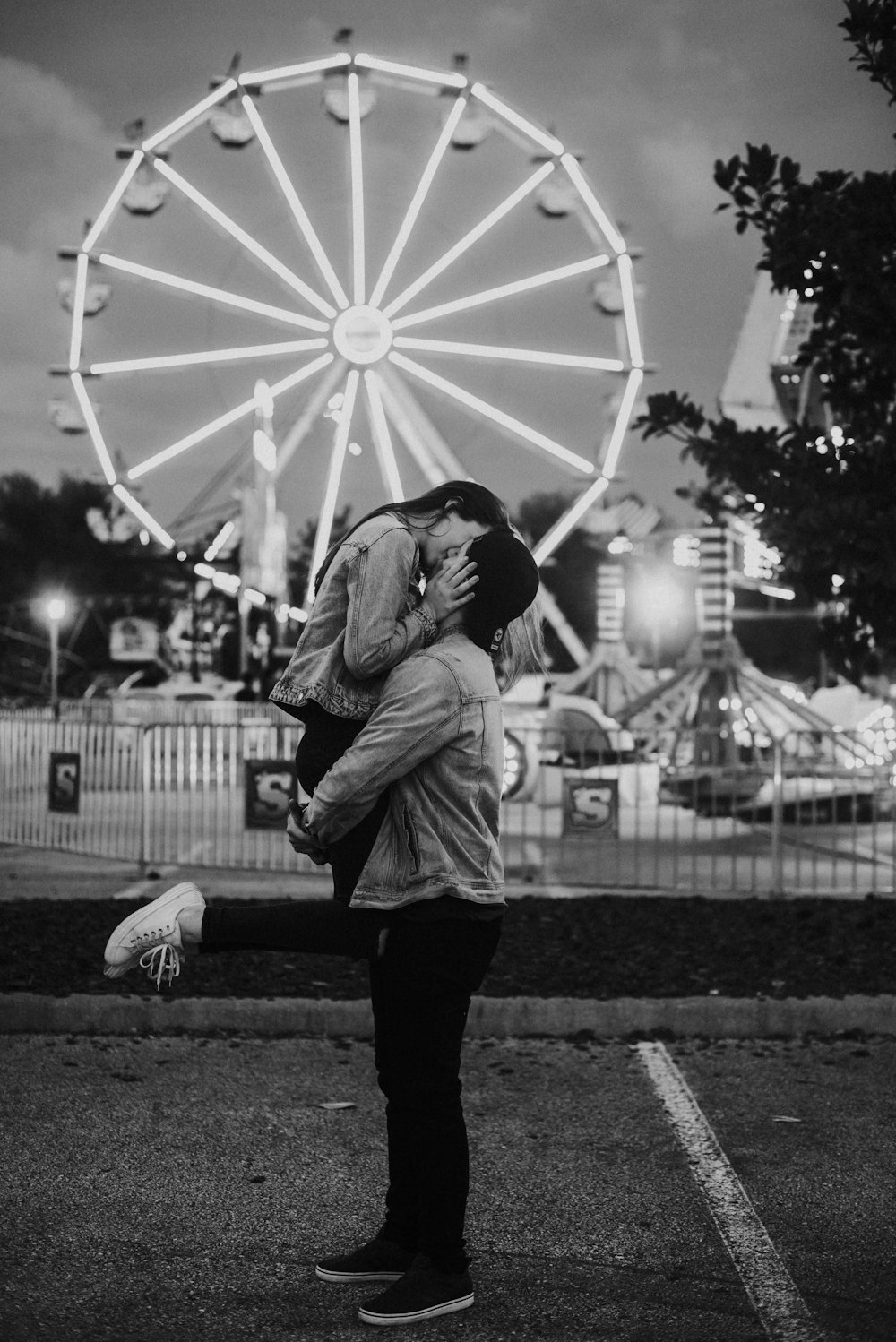 fotografia em tons de cinza do casal beijando em um parque de diversões