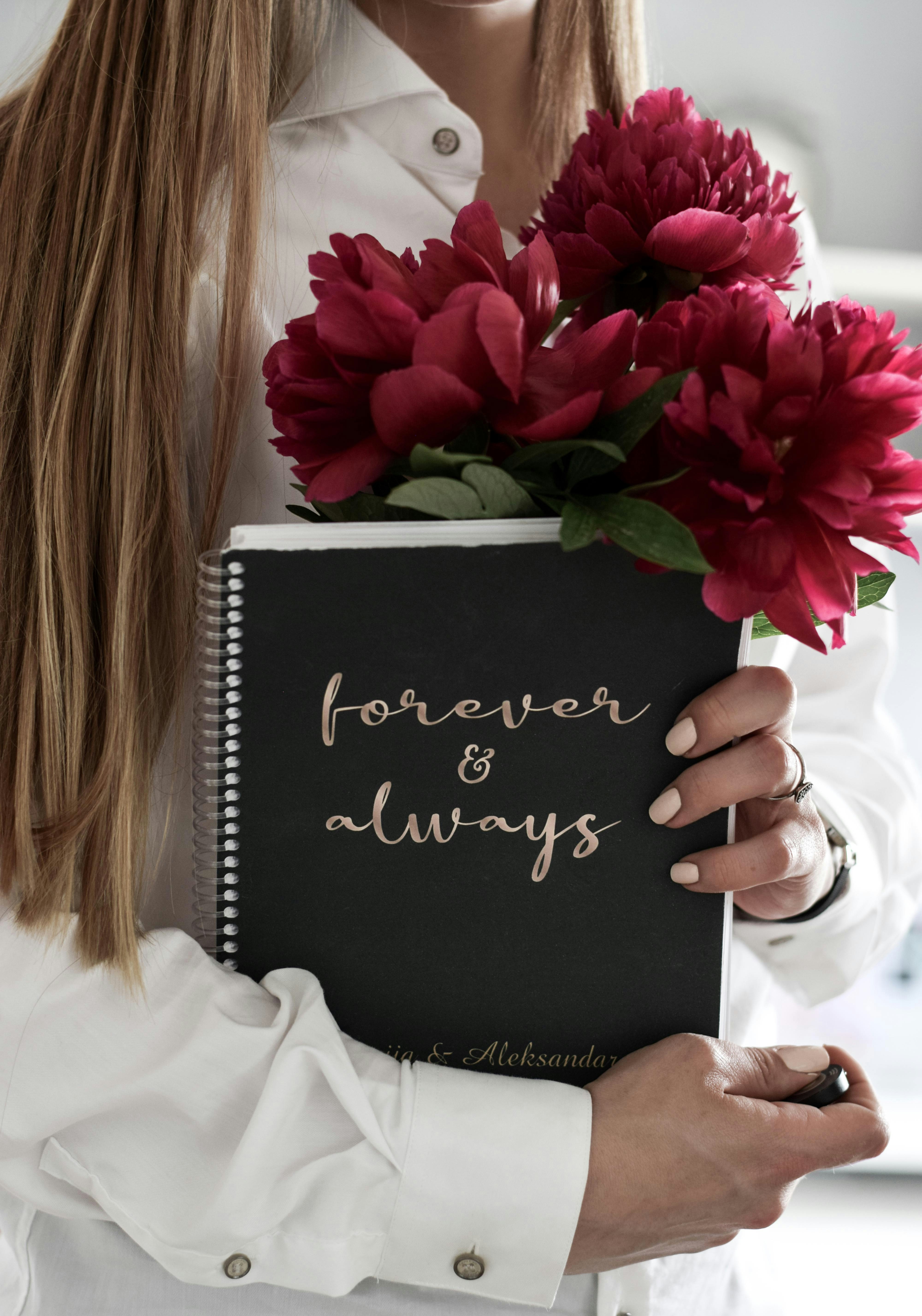 Frau in weißer Bluse mit Blume und Buch