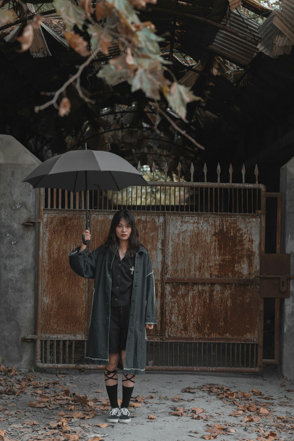 woman standing and holding umbrella near gate