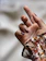 Close-up of perfectly manicured hands with glossy deep red nails against a soft beige background.