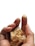 A hand is holding pieces of gold foil, with specks of the foil adhering to the fingertips. The background is a plain white, highlighting the contrast of the metallic shine.