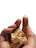 A hand is holding pieces of gold foil, with specks of the foil adhering to the fingertips. The background is a plain white, highlighting the contrast of the metallic shine.