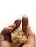 A hand is holding pieces of gold foil, with specks of the foil adhering to the fingertips. The background is a plain white, highlighting the contrast of the metallic shine.