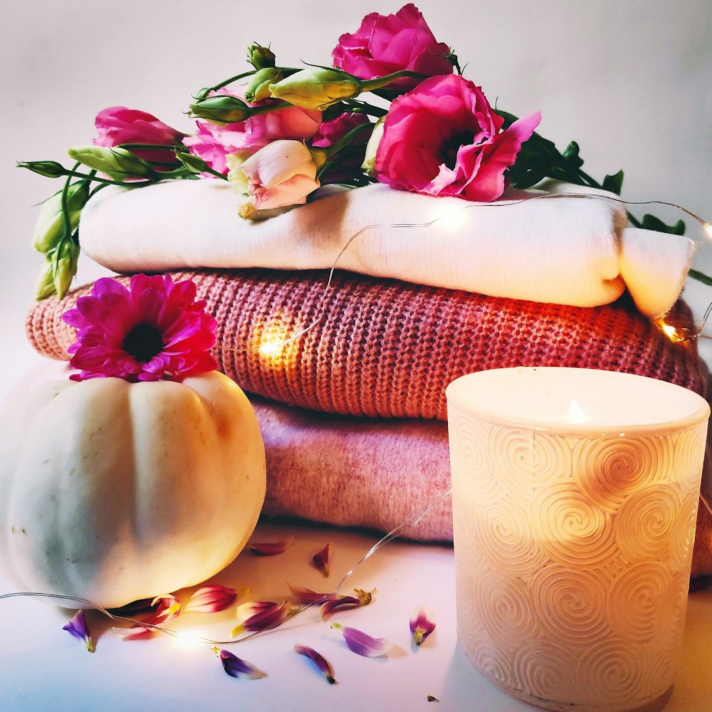 flowers on stack of textiles beside lit candle