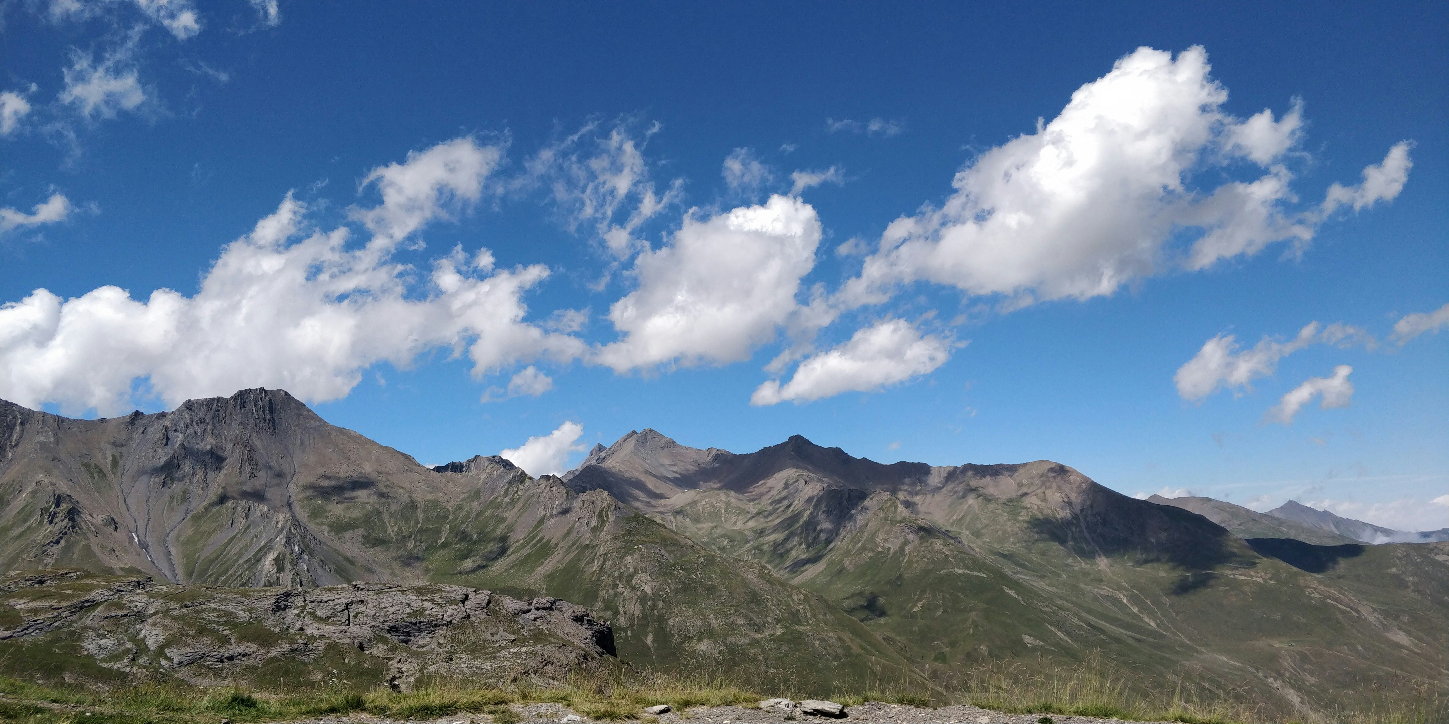 montagnes vertes sous un ciel nuageux pendant la journée