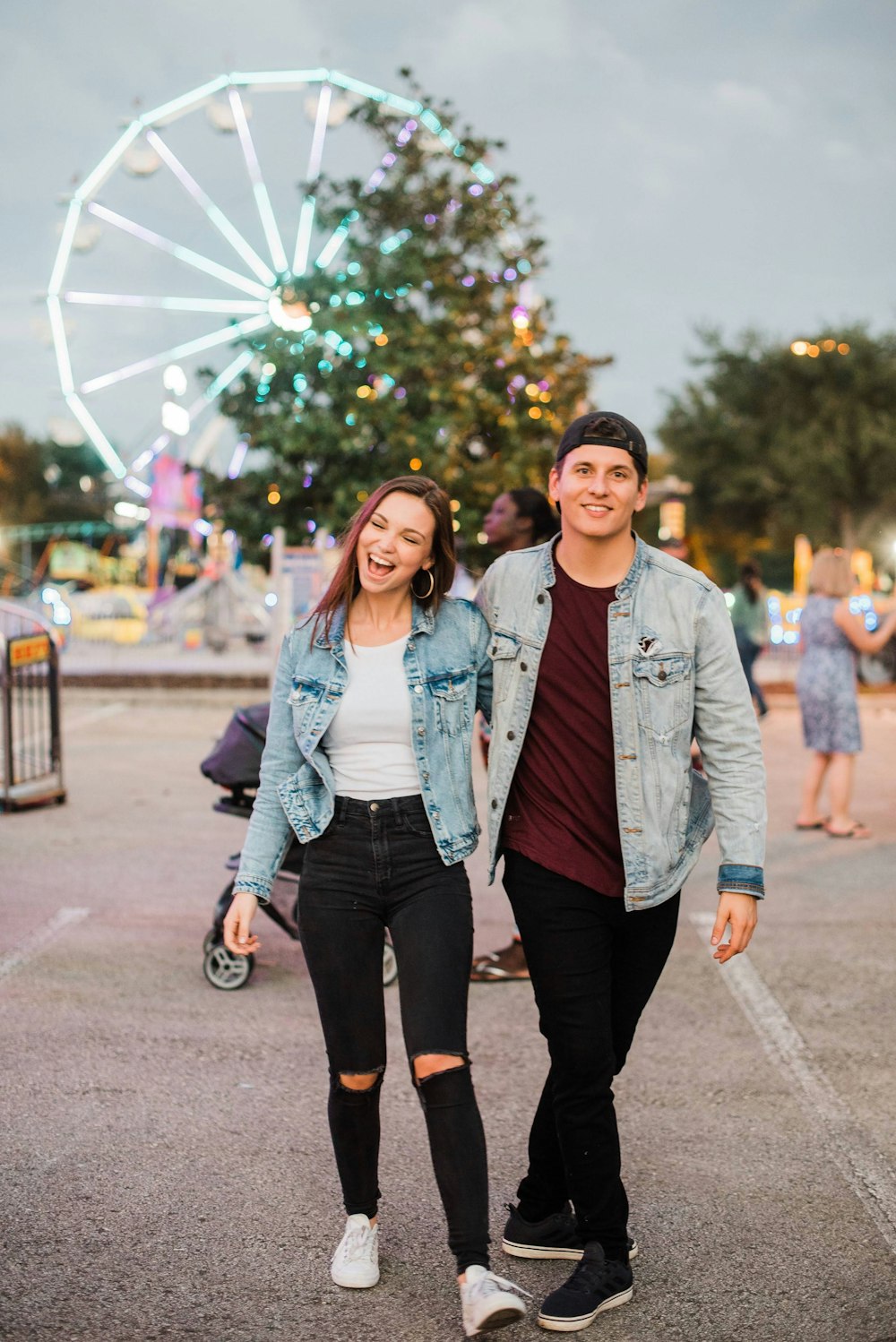 smiling man and woman wearing denim jackets and black pants