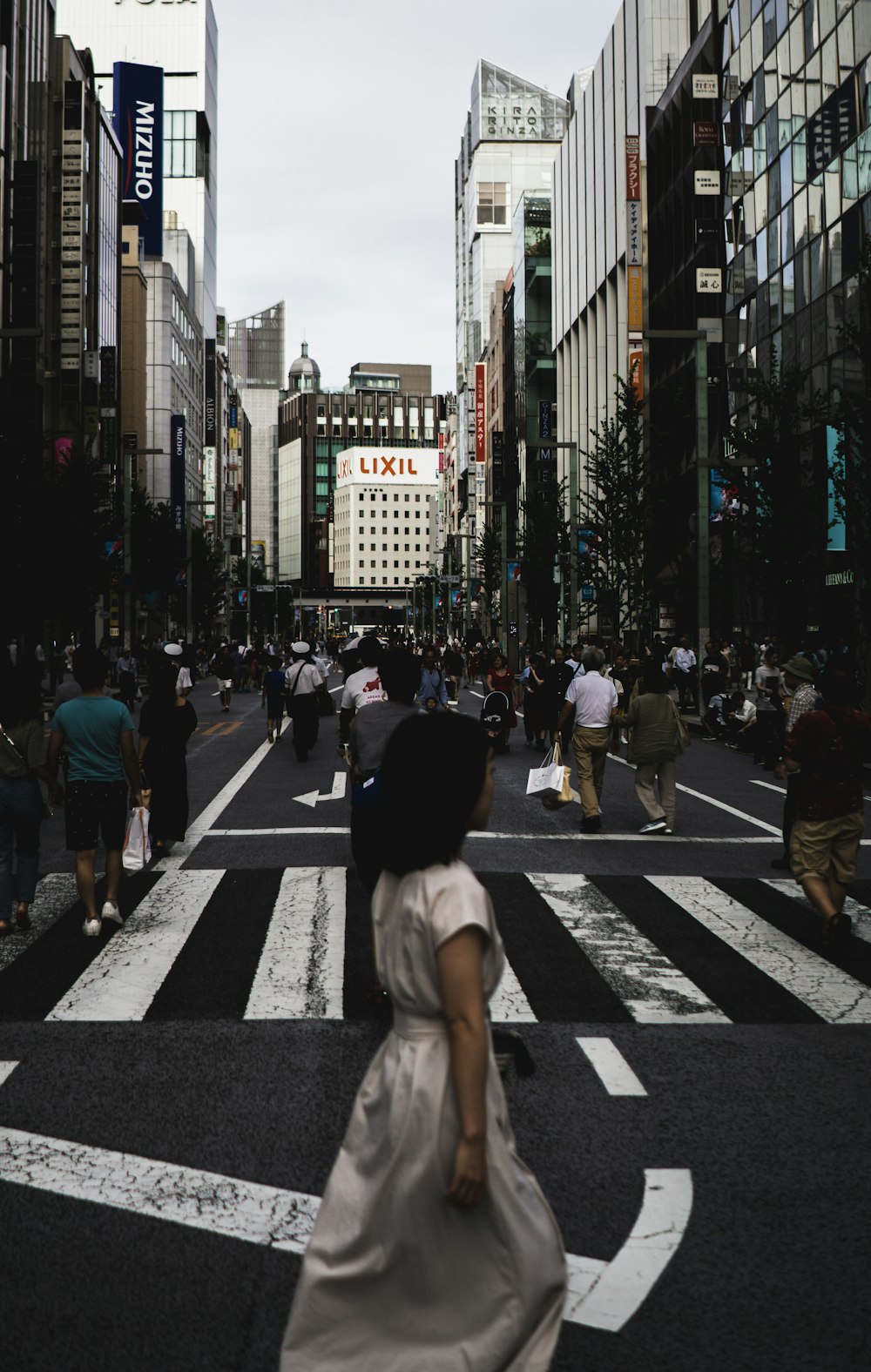 a woman walking across a cross walk in a city