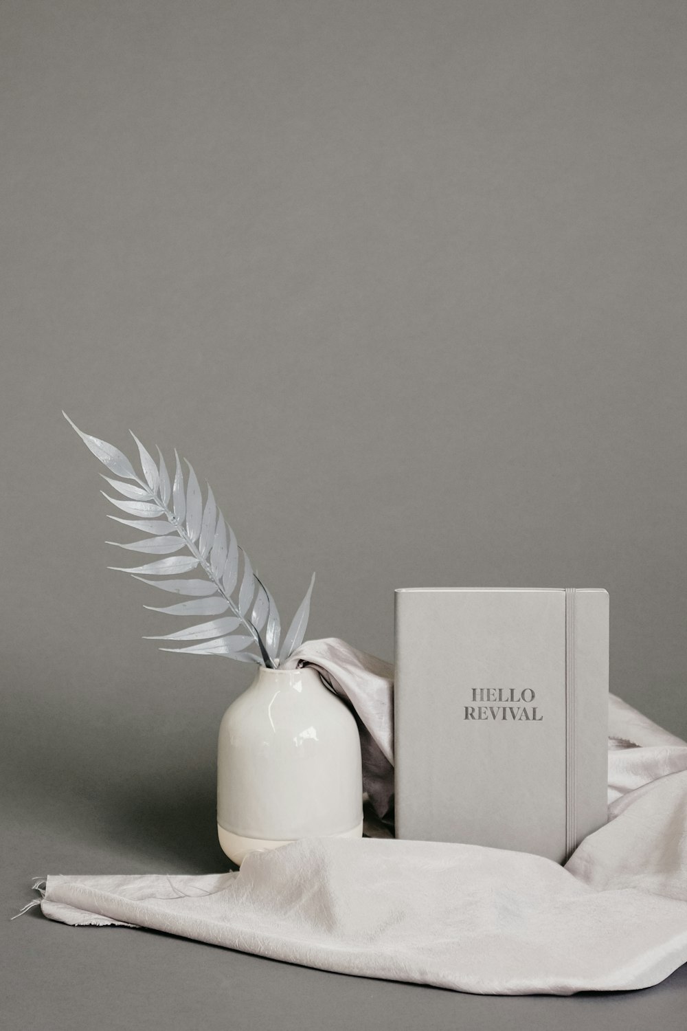 white ceramic vase beside notebook