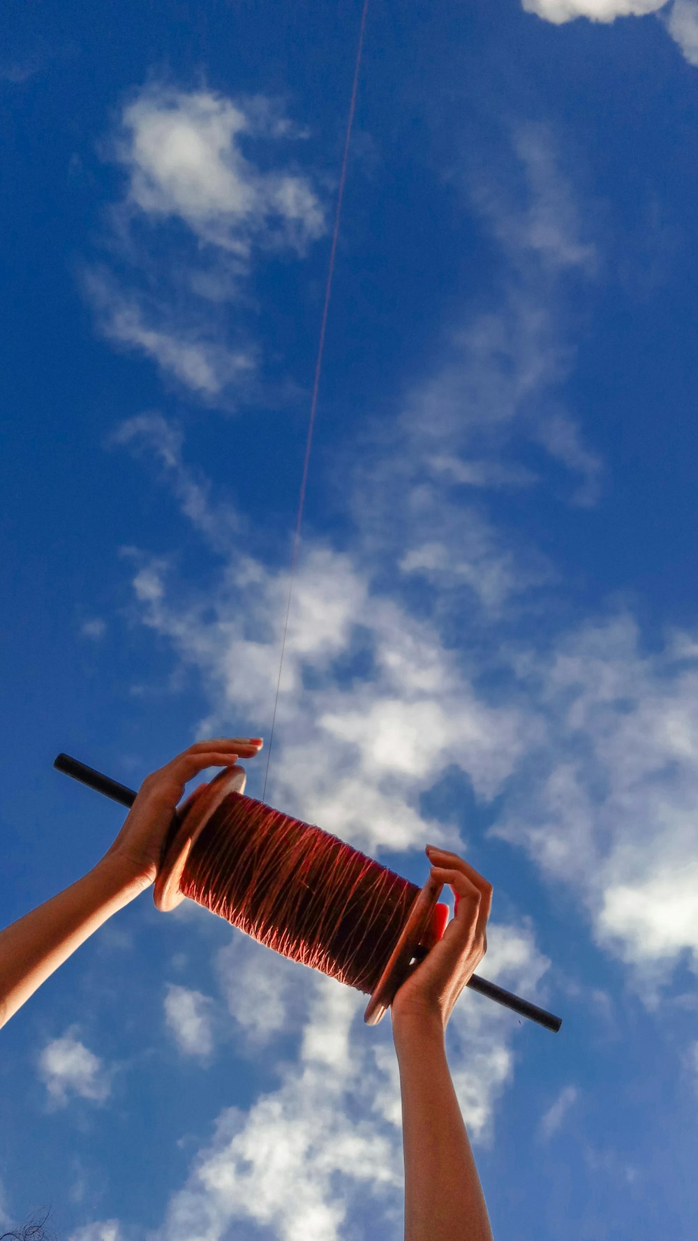 foto dal basso della bobina del filo dell'aquilone sotto il cielo nuvoloso