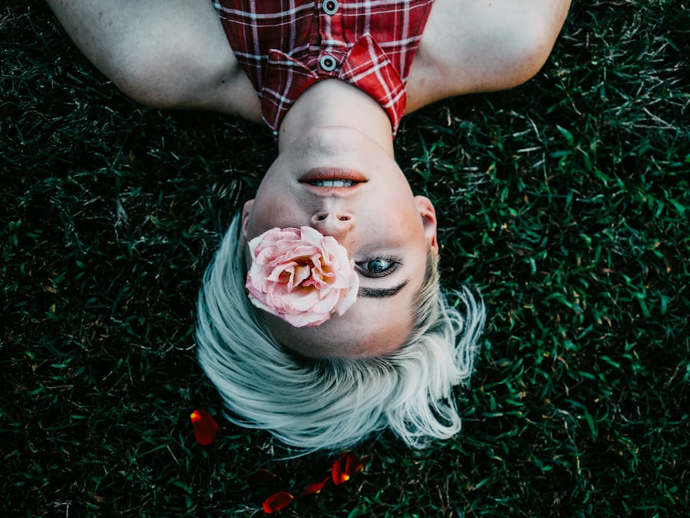 woman lying on grass with pink flower