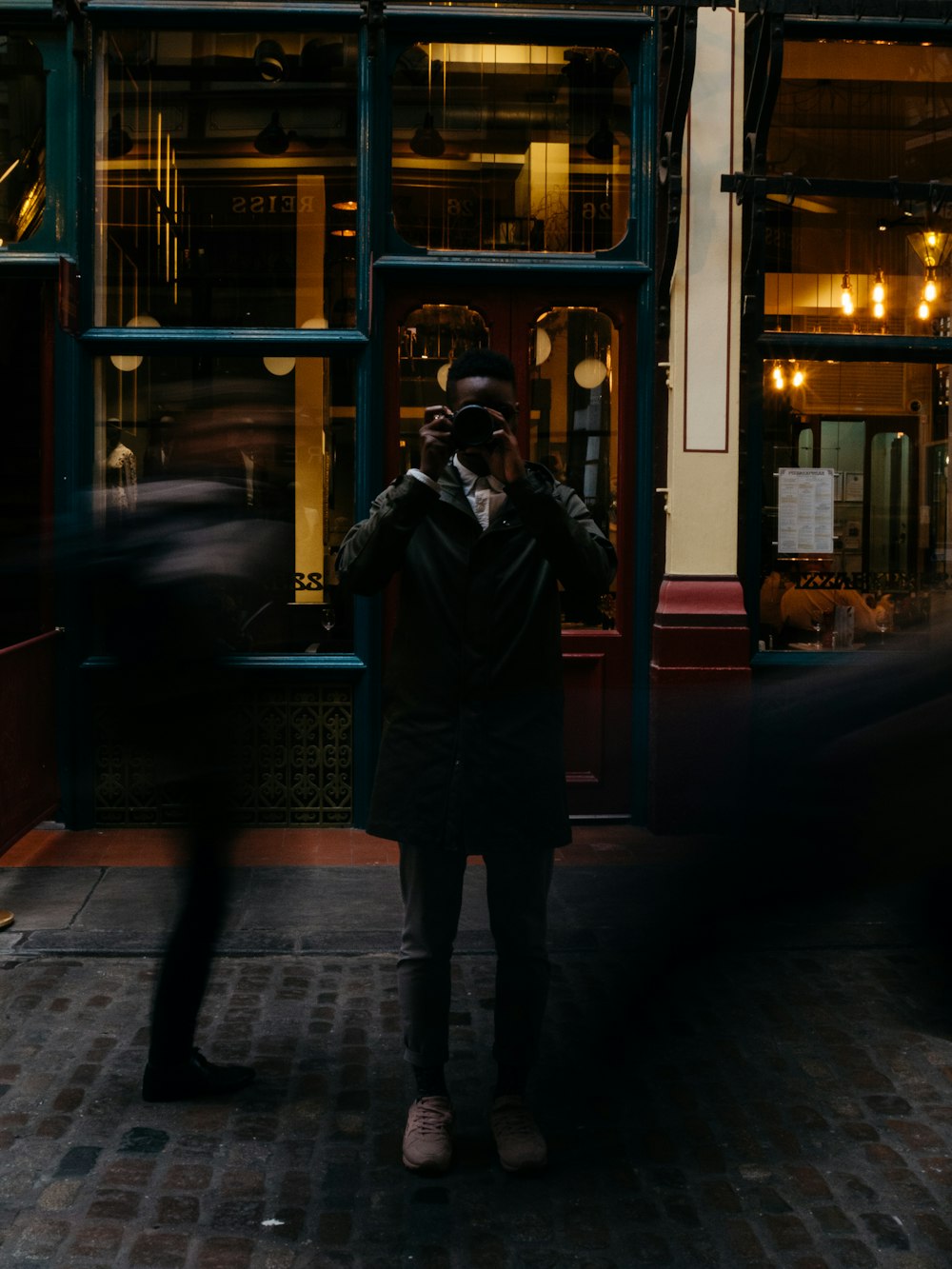 man wearing black pea coat using black DSLR camera
