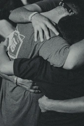 grayscale photography of men doing group hug
