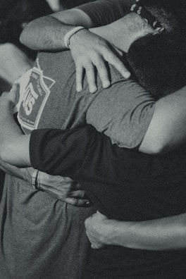 grayscale photography of men doing group hug