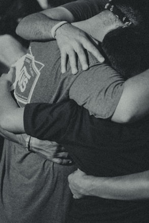 grayscale photography of men doing group hug