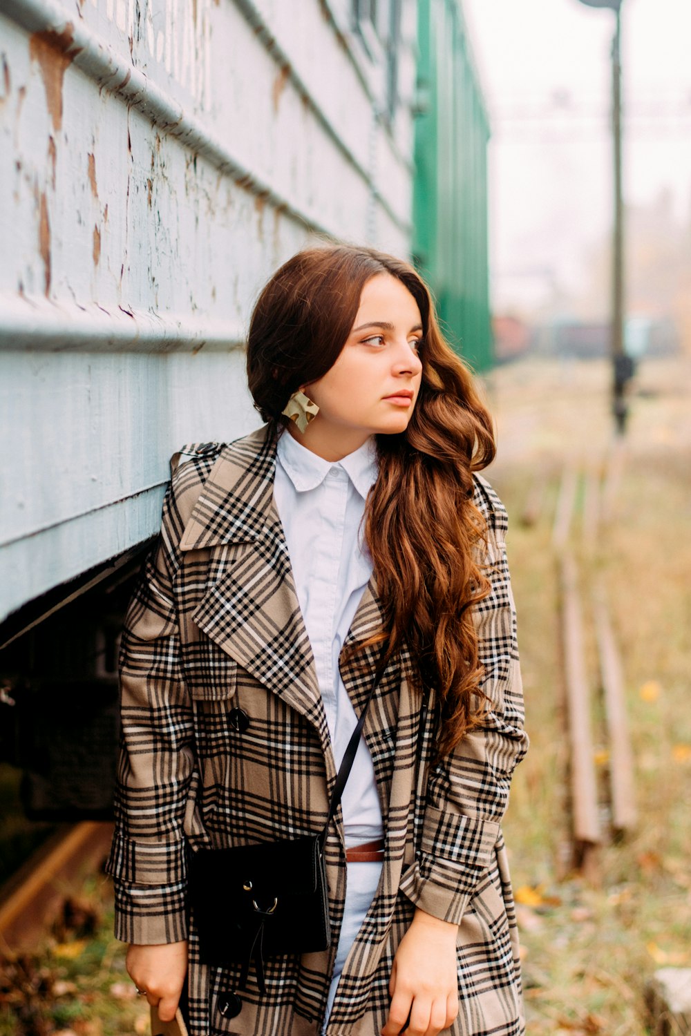 woman in black and brown plaid coat standing beside train wagon