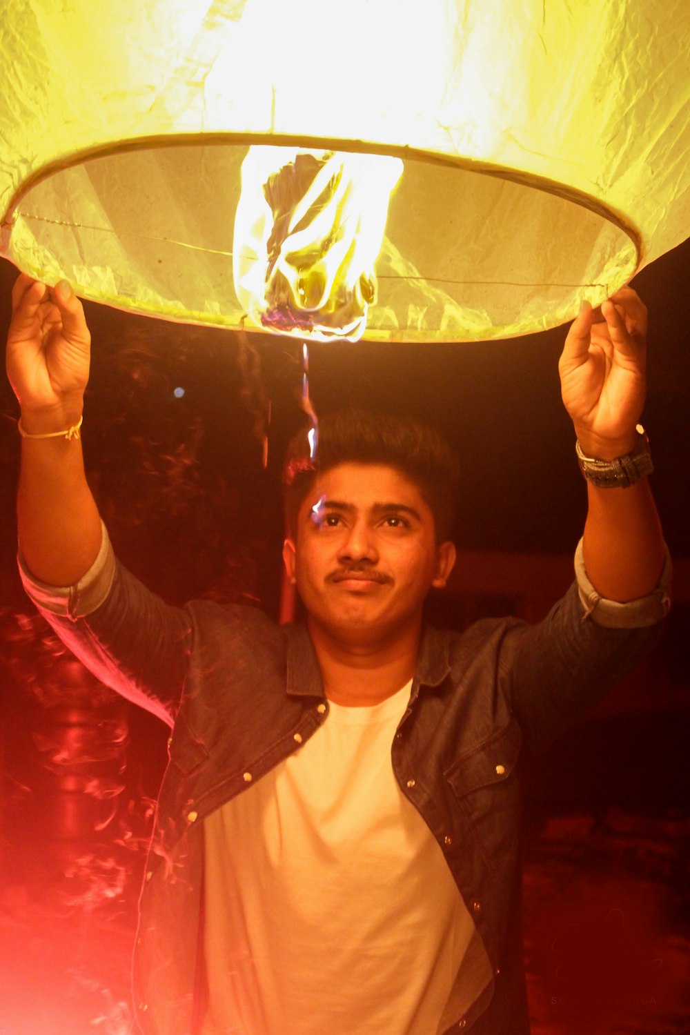 man holding on a lighted paper lantern
