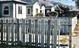 A small town street with neatly trimmed lawns and white picket fences.