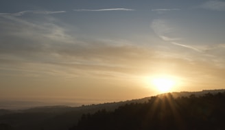 A radiant sunrise breaking over a vast, serene landscape symbolizing the dawn of creation.