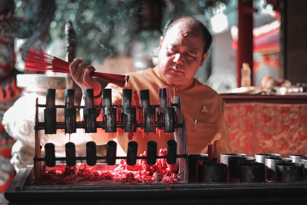 shallow focus photo of man holding incense