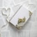 A collection of pages with text scattered around a white, decorative notebook adorned with a floral lace pattern. On top of the notebook lies a small bundle of dried flowers, and a ribbon forms the shape of a heart next to it.