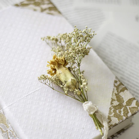 Elegant ivory resin flower arrangement resting on a light fabric background with airy botanical details.