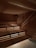 A wooden sauna with tiered seating is depicted, featuring warm lighting that casts a patterned glow on the walls and ceiling. A towel is placed on one of the benches.