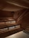 A wooden sauna with tiered seating is depicted, featuring warm lighting that casts a patterned glow on the walls and ceiling. A towel is placed on one of the benches.
