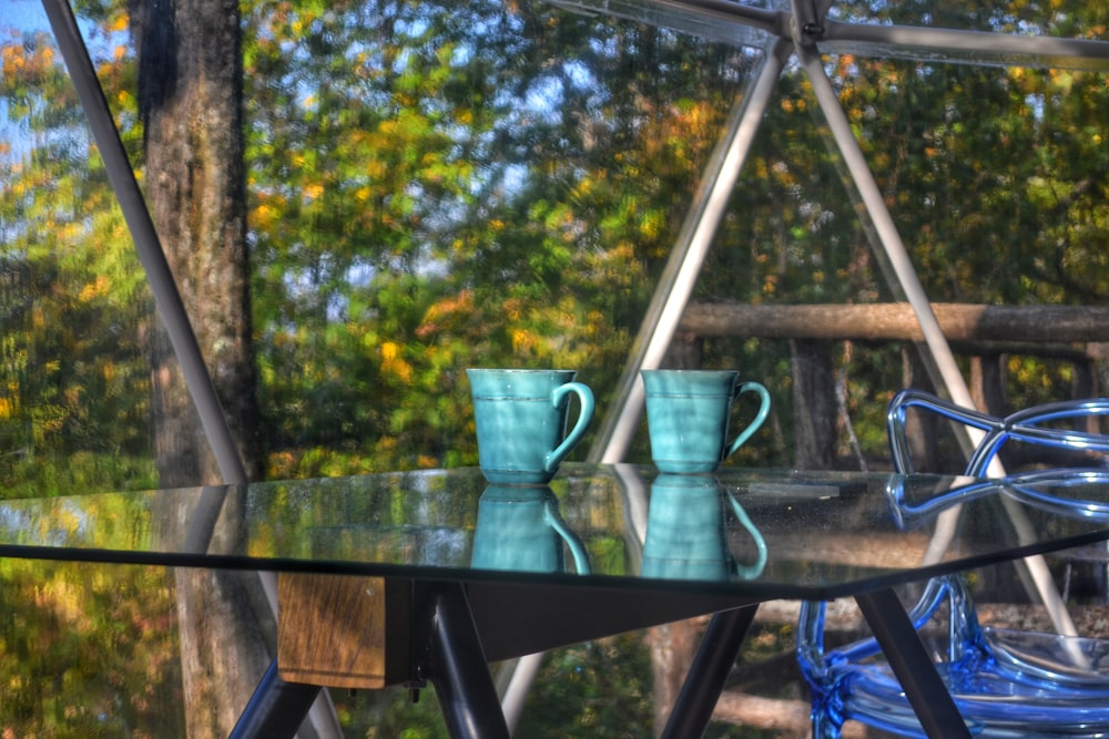 two blue ceramic mugs on top of a glass top table