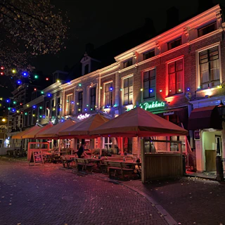 A lively street scene showcasing a popular local business illuminated with gold accents at night.