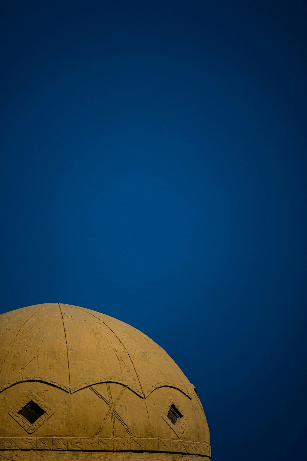 brown concrete dome building under a calm blue sky