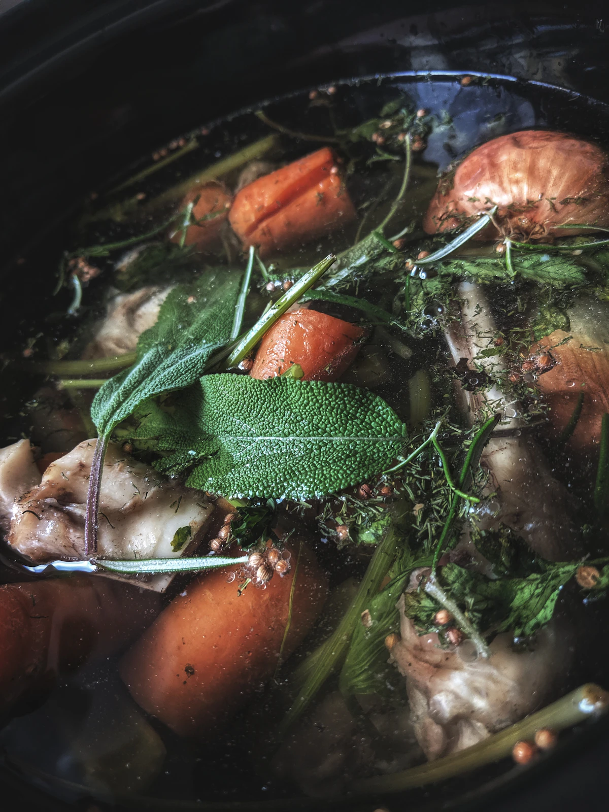 Bowl of bone broth with vegetables and herbs