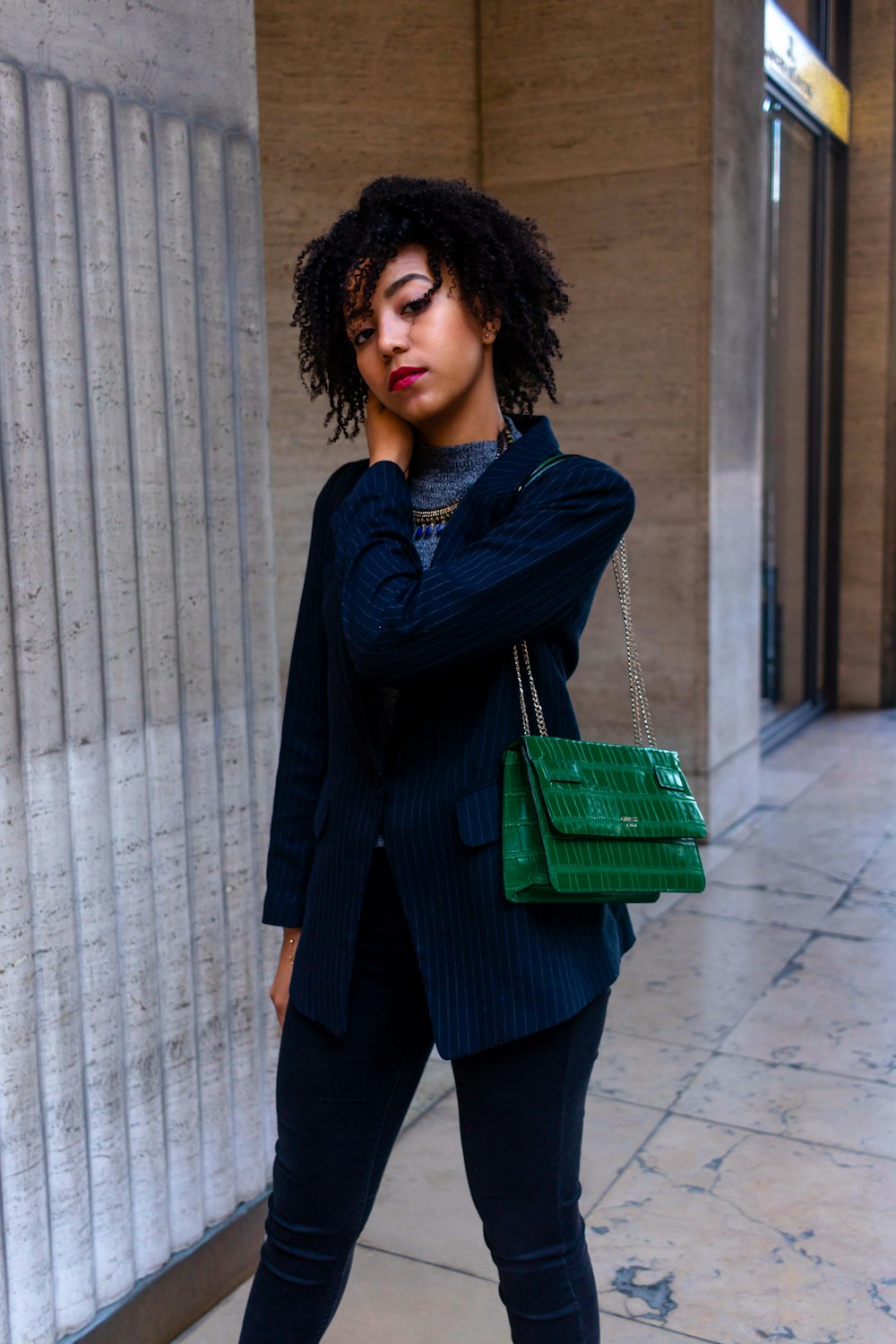 woman in dark-blue blazer carrying green shoulder ba