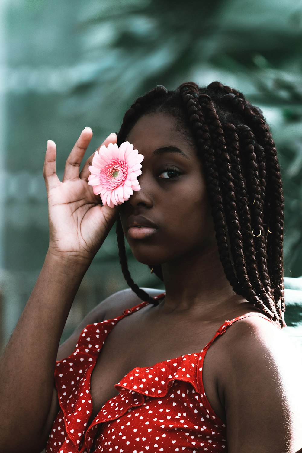 woman in white red dotted spaghetti strap top covering right eye with pink daisy