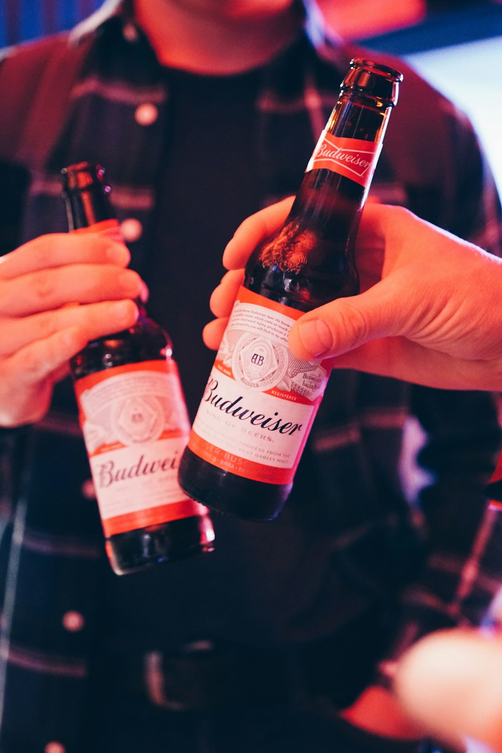two persons holding white Budweiser bottles