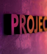 The word 'PROJECTS' appears in large, bold, three-dimensional letters against a textured surface, with vibrant lighting that transitions from purple to orange, creating a dynamic gradient effect.