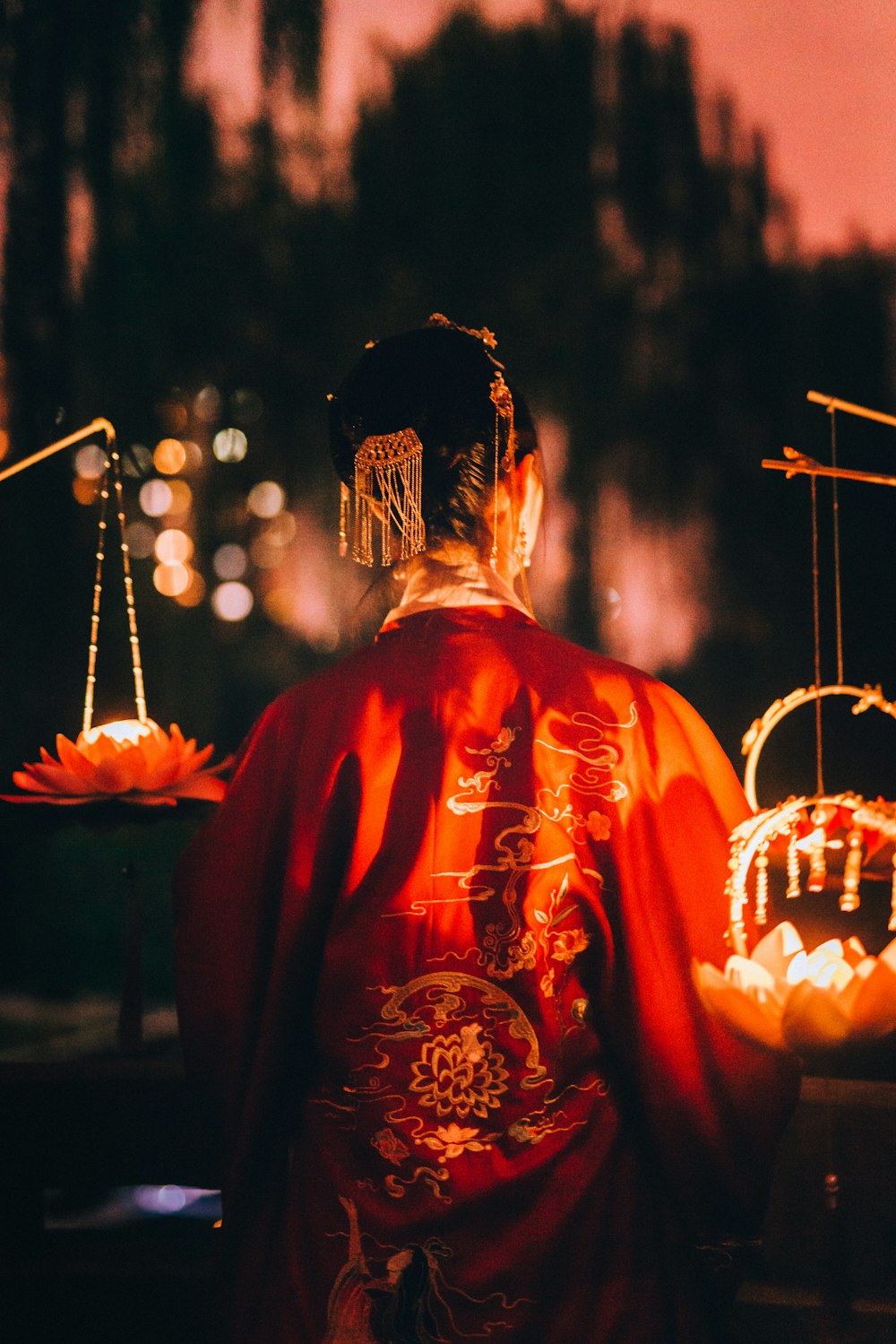 woman wearing red traditional dress beside pendant lamps at night