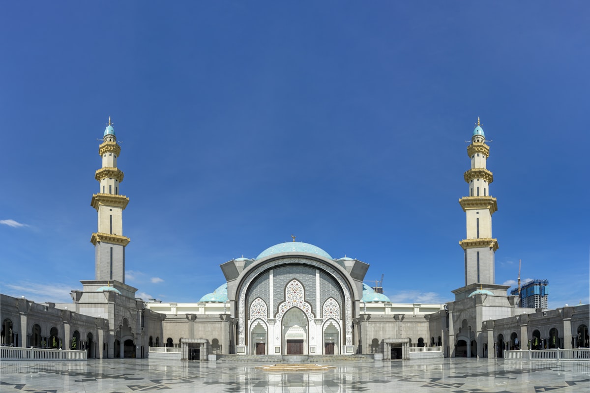 Kuala Lumpur January — Masjid Wilayah Persekutuan mosque with twin gold minarets and grand courtyard under clear blue sky