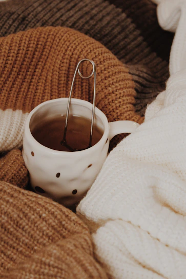 A cheerful ceramic mug with bright yellow glaze, steam rising from a hot drink, set against a cozy knitted blanket.