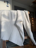 Close-up of a ribbed cotton throw blanket draped over a cozy armchair.