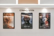 Three framed movie posters are displayed on a wall beneath the text 'COMING SOON.' The central poster features the title 'Gemini Man,' while the other two posters are in another language and contain action-themed imagery.