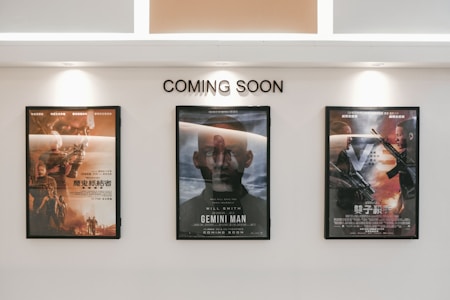 Three framed movie posters are displayed on a wall beneath the text 'COMING SOON.' The central poster features the title 'Gemini Man,' while the other two posters are in another language and contain action-themed imagery.