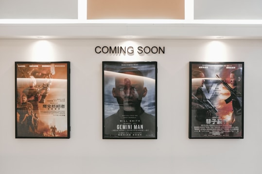 Three framed movie posters are displayed on a wall beneath the text 'COMING SOON.' The central poster features the title 'Gemini Man,' while the other two posters are in another language and contain action-themed imagery.